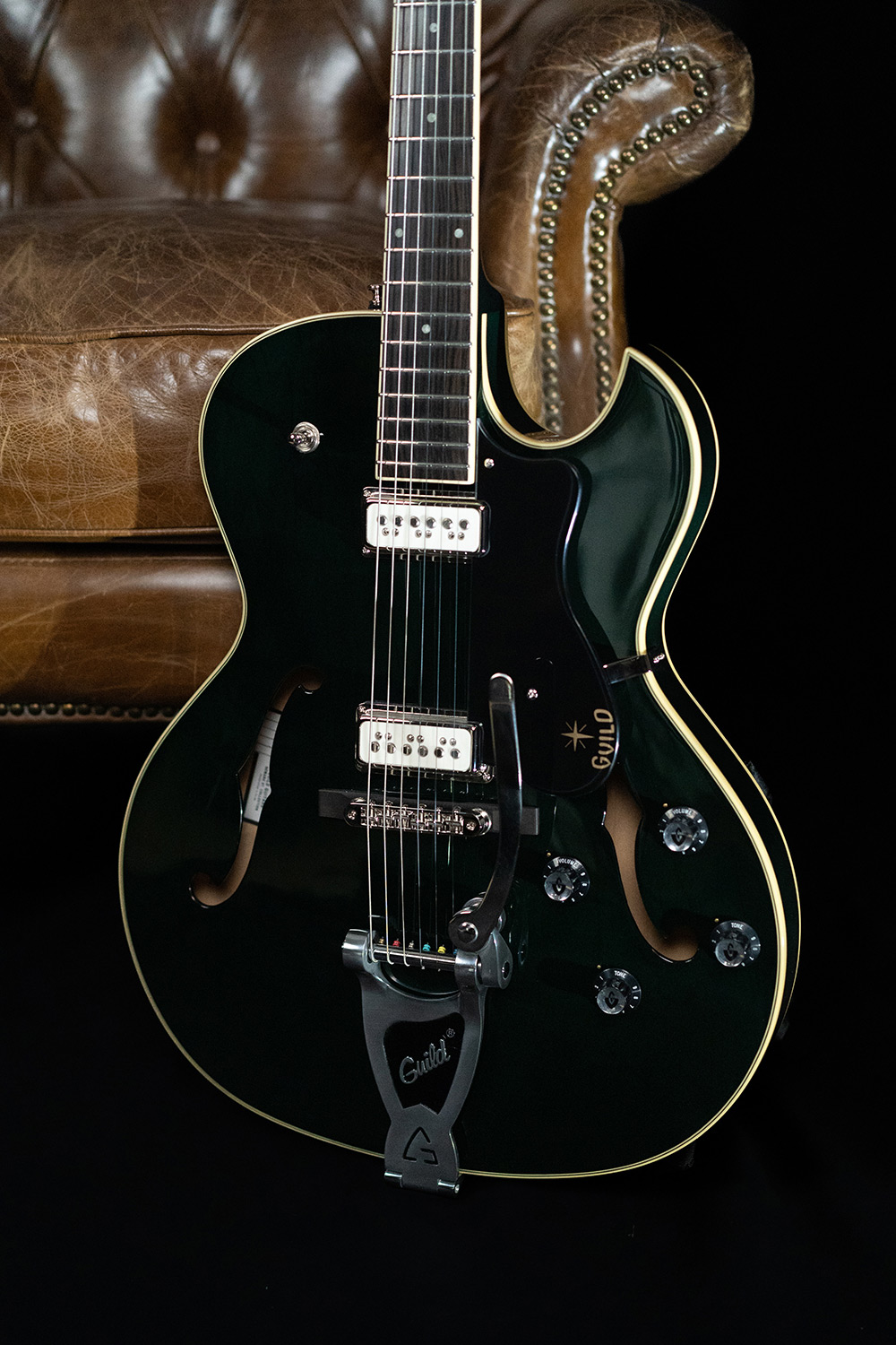 Close up view of Starfire III Dynasonic Emerald Green body with guitar leaning against a leather chair