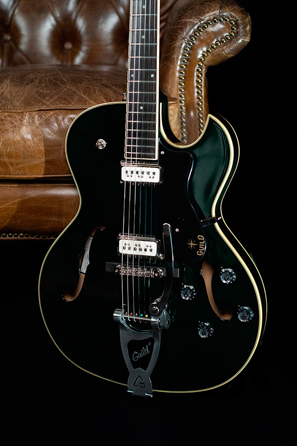 Close up view of Starfire III Dynasonic Emerald Green body with guitar leaning against a leather chair thumbnail