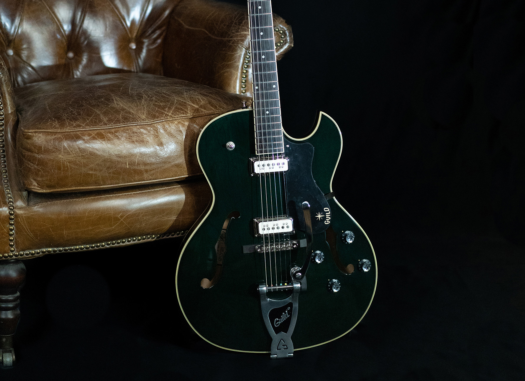 Starfire III Dynasonic Dark Emerald leaning against a leather chair