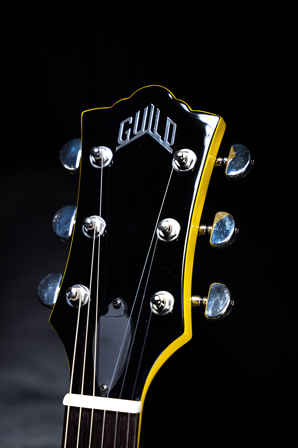 Close up of Polara Voltage Yellow headstock showcasing Guild Peak Logo