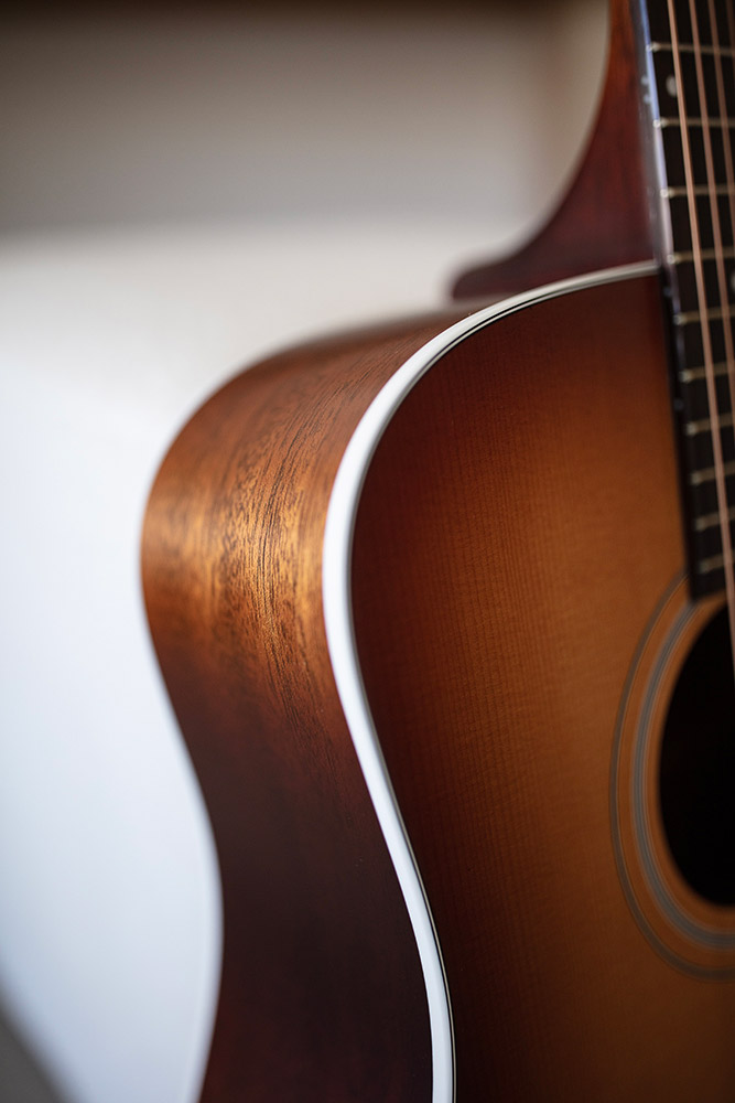 Close-up of D-40 Standard Pacific Sunset Burst curve highlighting the body binding and solid African mahogany side