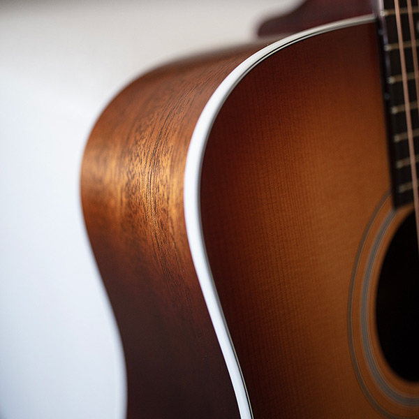 Close-up of D-40 Standard Pacific Sunset Burst curve highlighting the body binding and solid African mahogany side thumb