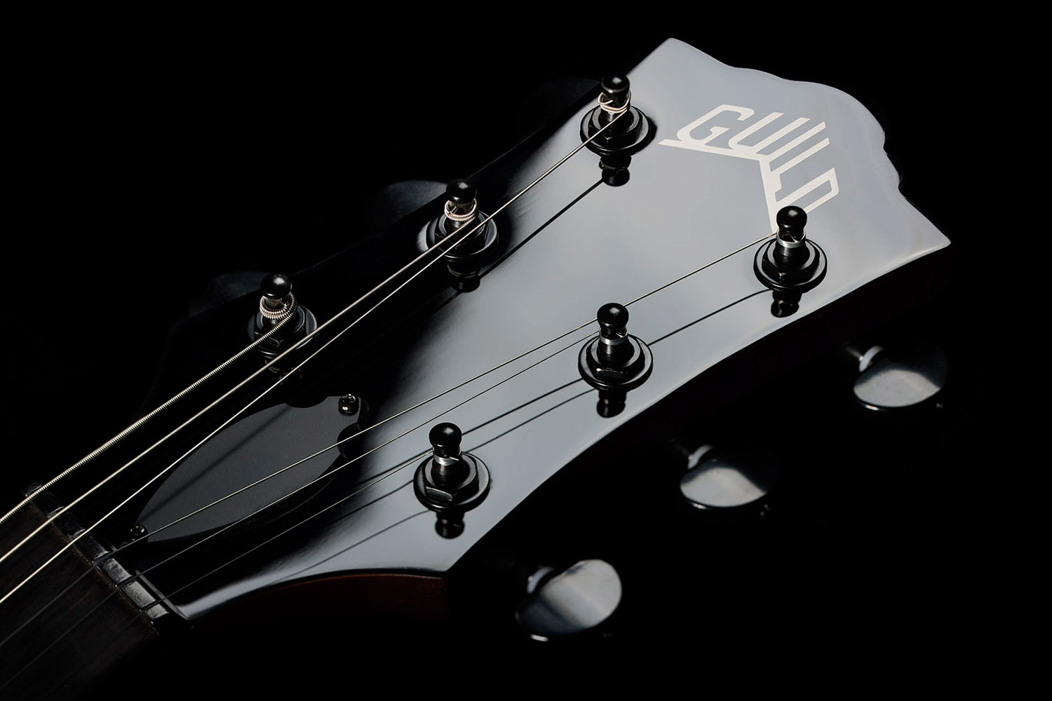Close-up of Polara Limited Night Edition Vintage Walnut headstock with Guild Peak logo