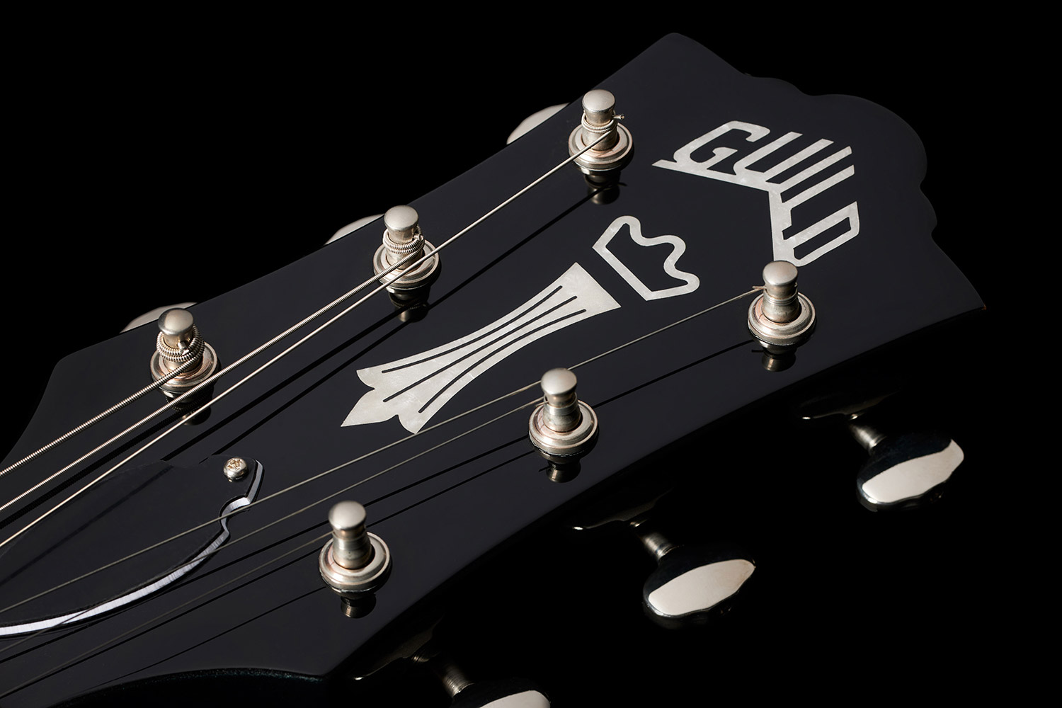 Close-up of the Polara Deluxe Kingswood Green headstock featuring Guild Peak logo