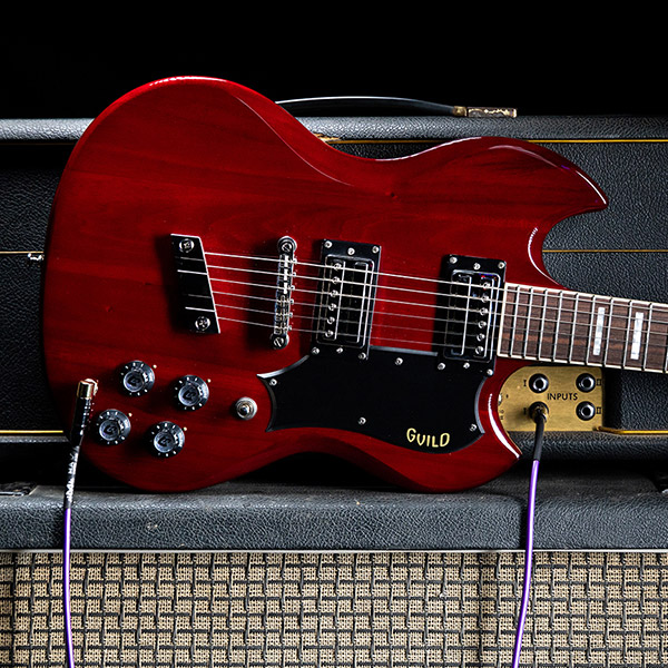 Polara Deluxe Cherry Red laying horizontal on top of a guitar amp thumb