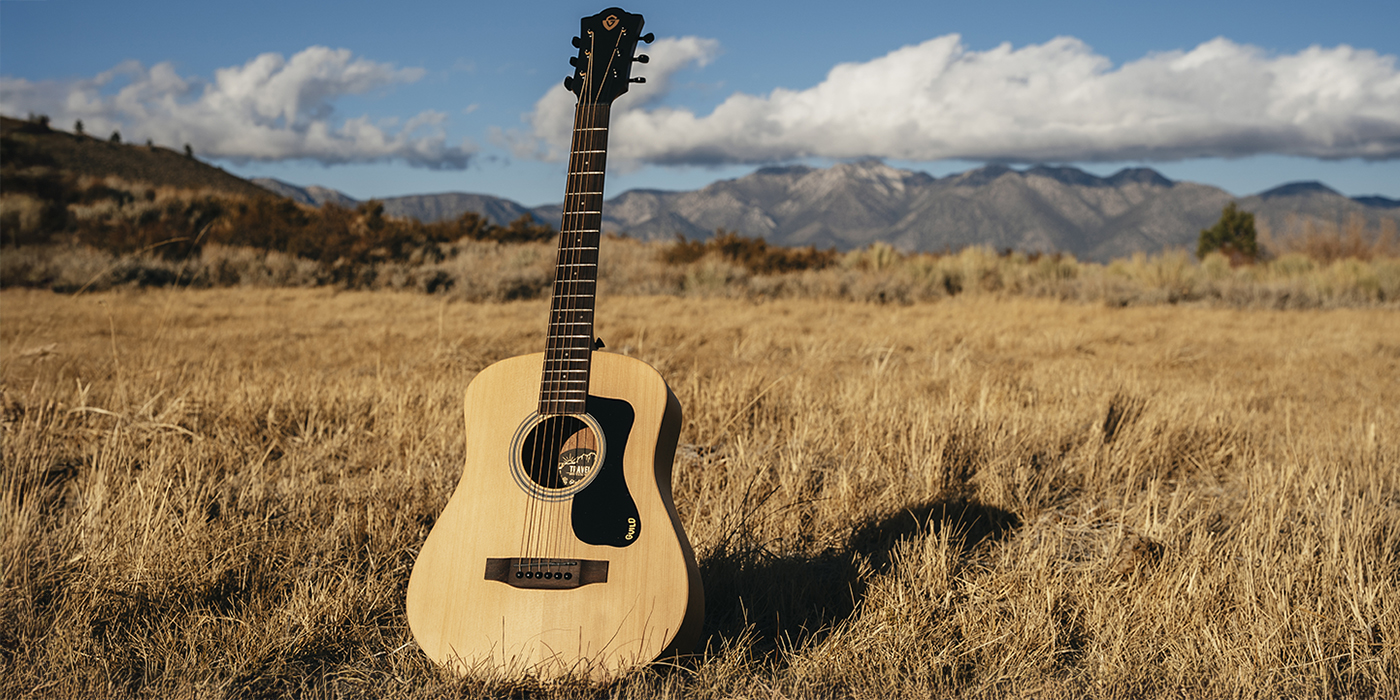 Travel Spruce acoustic guitar in a outdoor field setting