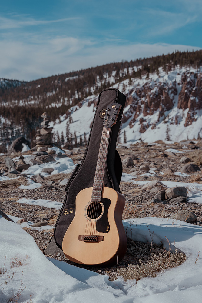 Travel Spruce acoustic guitar with gig bag  in a rocky snowy landscape