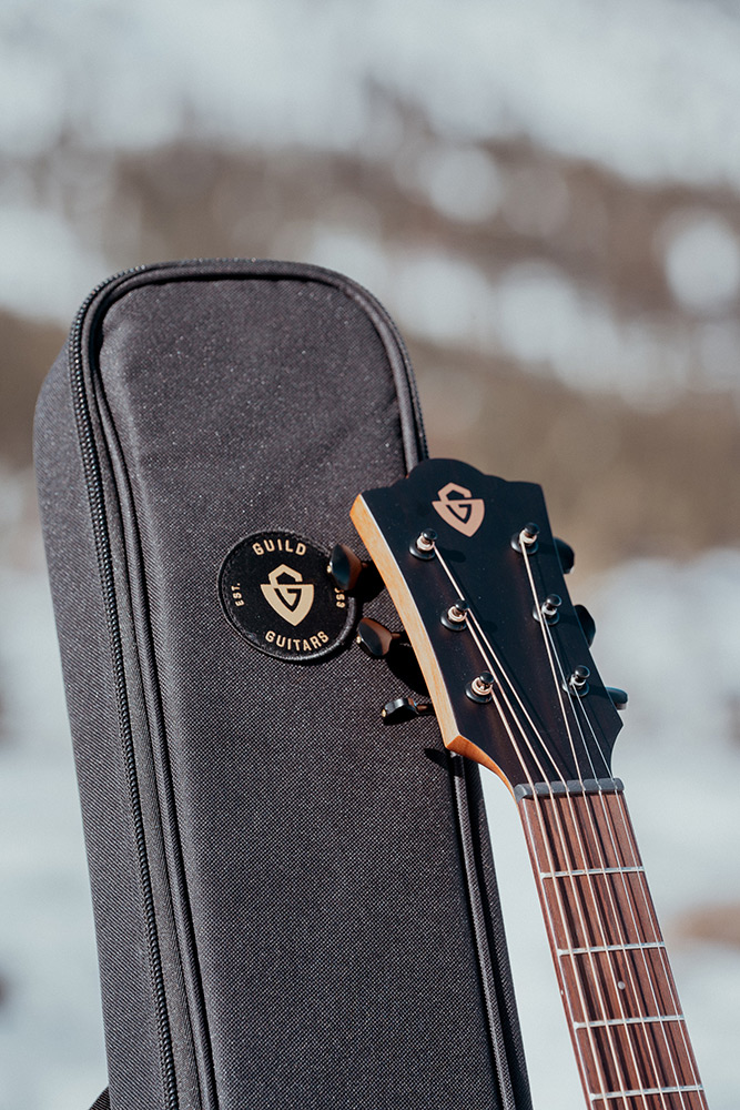 Close up of Travel Spruce head stock and top of gig bag with snowy landscape behind