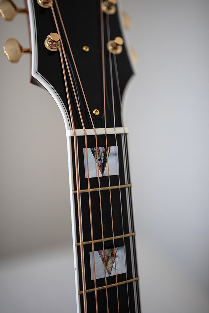 Close-up of GSR D-55 70th Anniversary Limited acoustic guitar's body, featuring a decorative pickguard with a marbled design and visible strings.